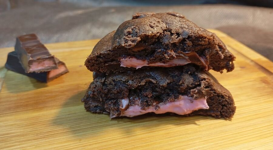 Cookie de chocolate recheado partido ao meio mostrando o recheio cremoso